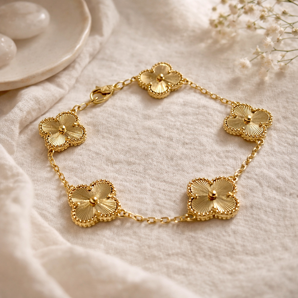 Gold bracelet with floral designs on a soft beige fabric background