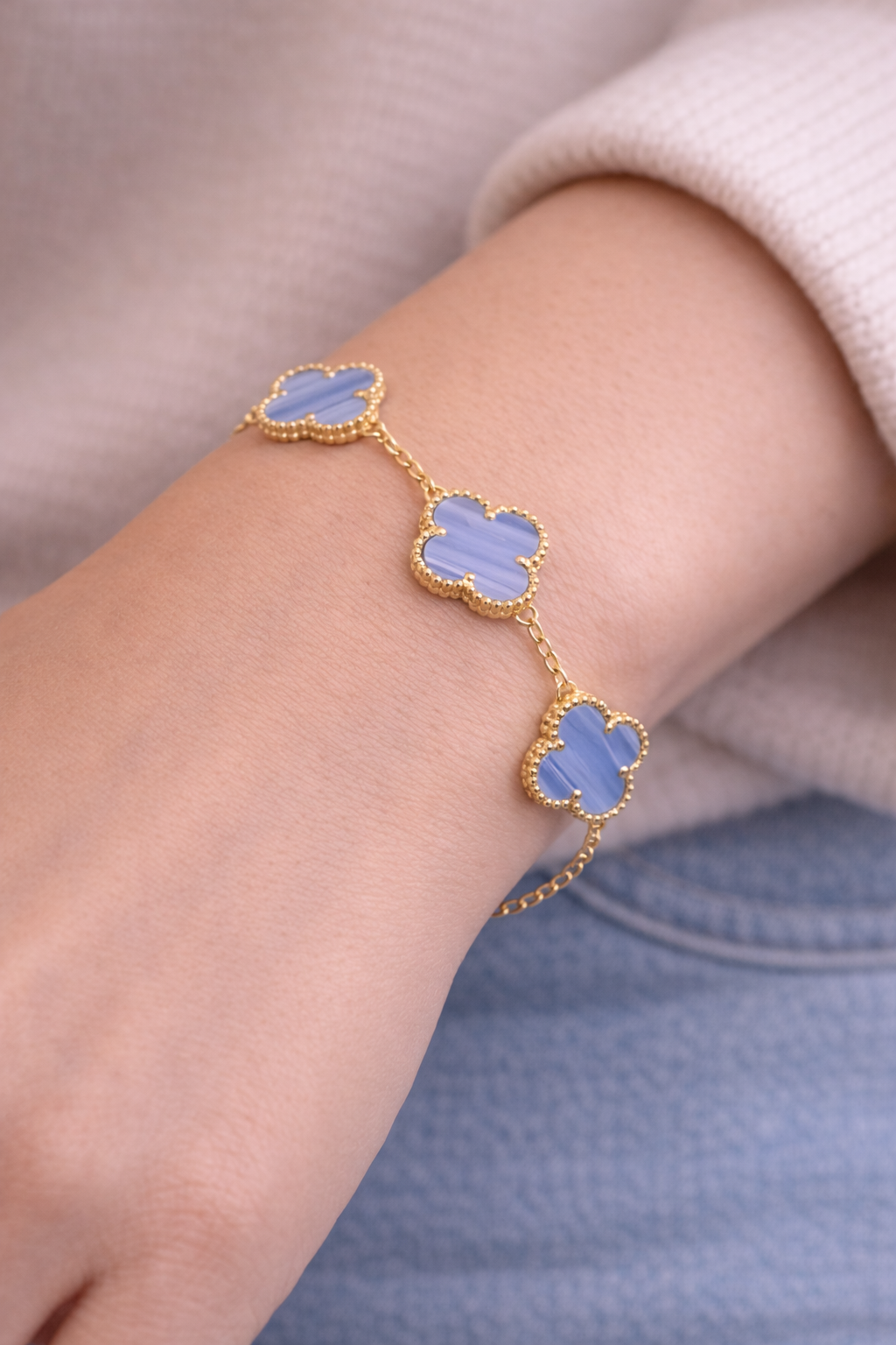 Blue clover-shaped bracelet on a wrist with a neutral background