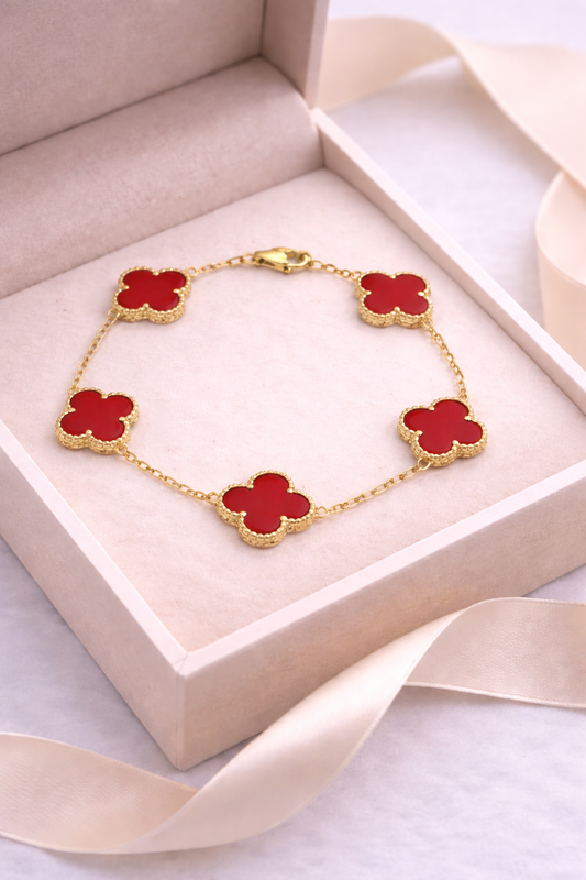 Gold bracelet with red clover-shaped charms in a jewelry box