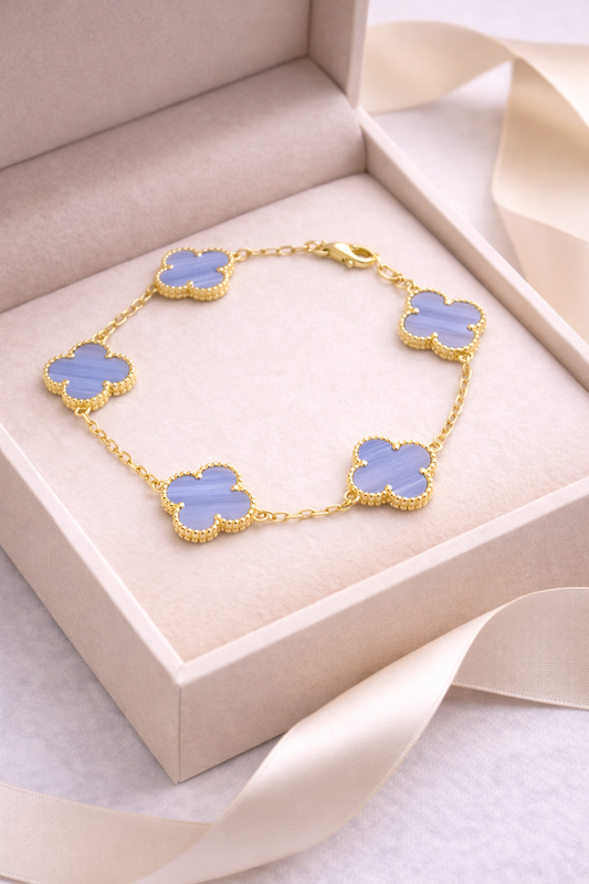 Gold bracelet with blue clover-shaped charms in a beige box
