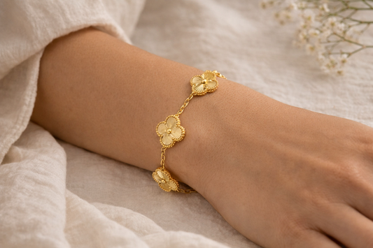 Gold bracelet with floral designs on a wrist against a soft background