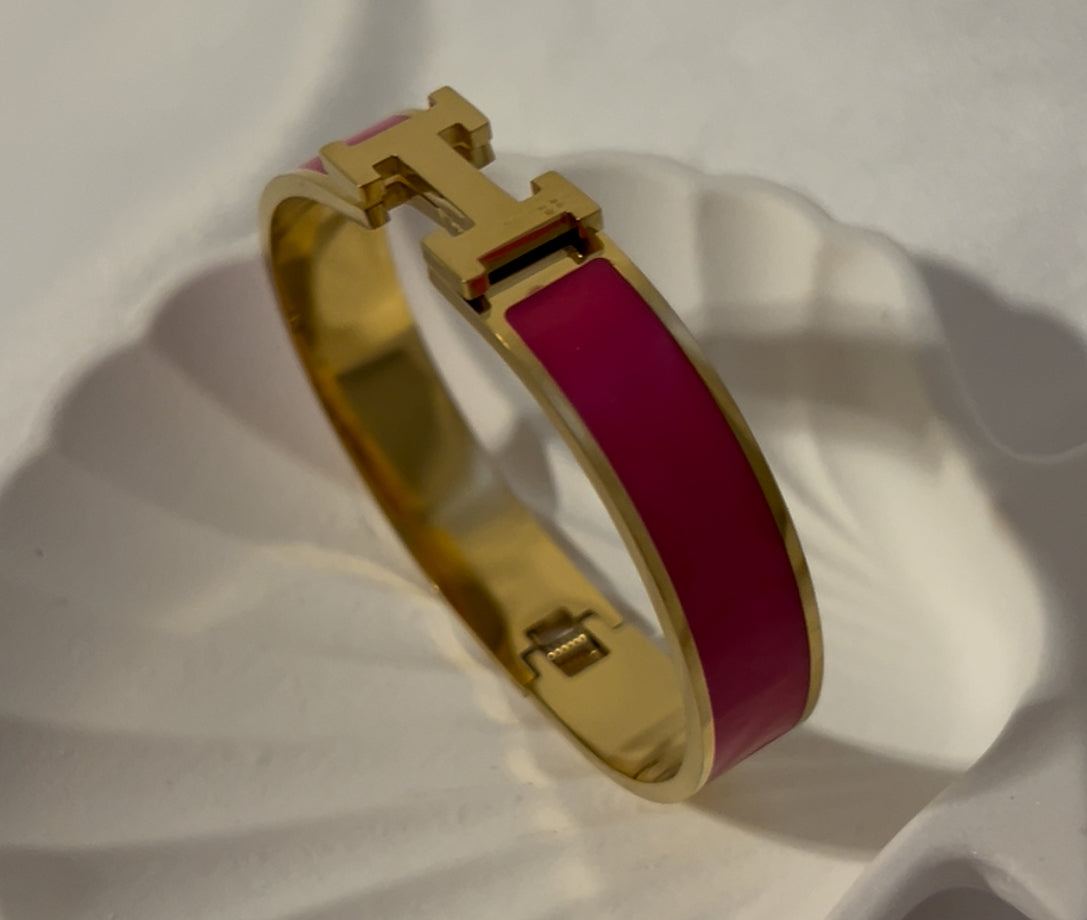 Side angle of magenta H bangle bracelet with glossy enamel and gold finish, modern elegant bracelet