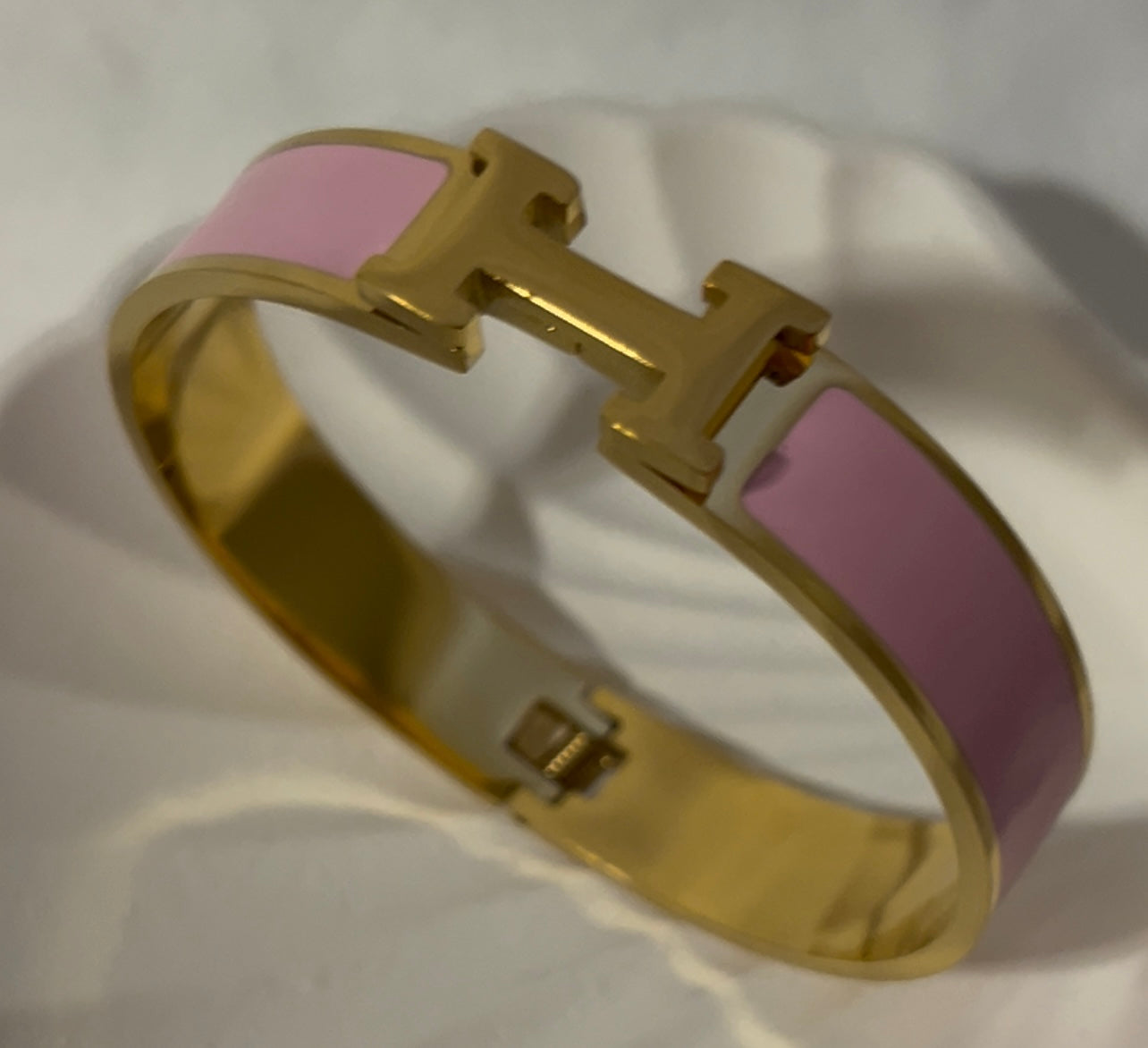 Side angle of pink H bangle bracelet with glossy enamel and gold finish, modern elegant bracelet