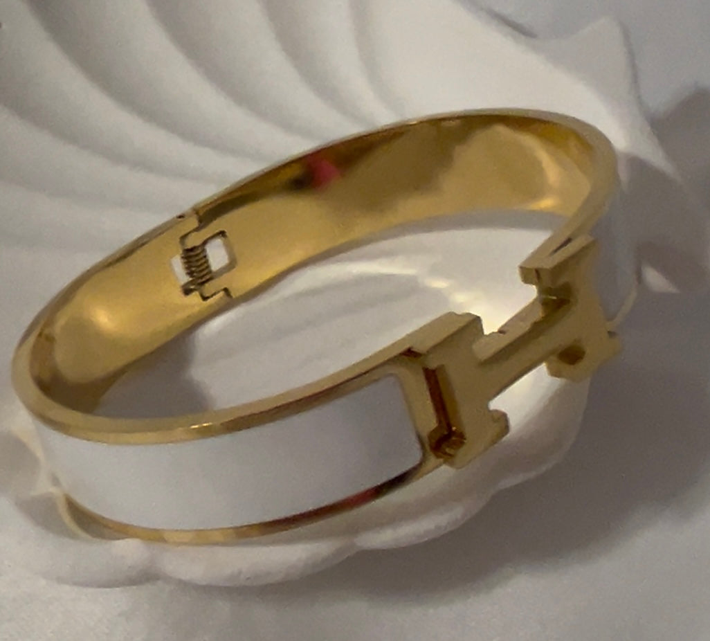 Close-up of white H bangle bracelet showing smooth enamel texture and premium gold plating